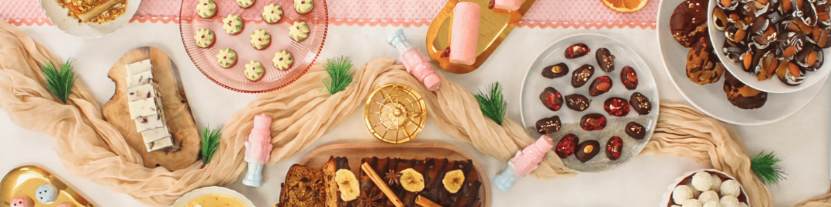 A Christmas banquet table with chocolate nutcracker figures, chocolate Christmas puddings, banana and date loaf, chocolate dipped dates and Asian style decor