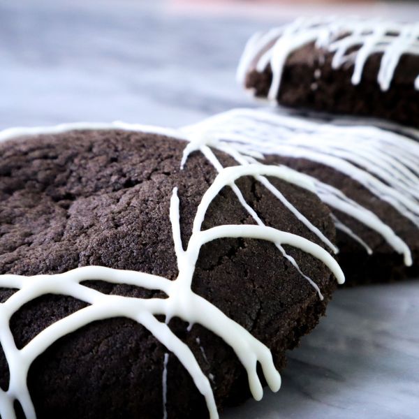 Chocolate biscuits drizzled with white icing arranged on a surface