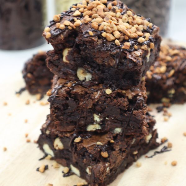Stacked chocolate brownies with nut pieces and chopped nuts on top