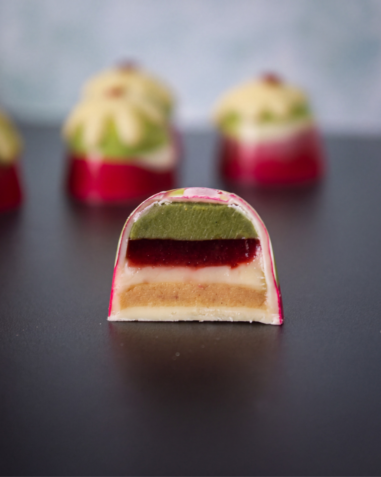Matcha and cherry Christmas pudding bonbon cut open to reveal layers of matcha, cherry, mascarpone and biscuit.