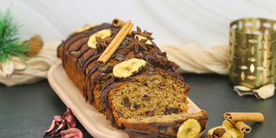 Vegan banana and date bread topped with dark chocolate, banana pieces and festive spices.